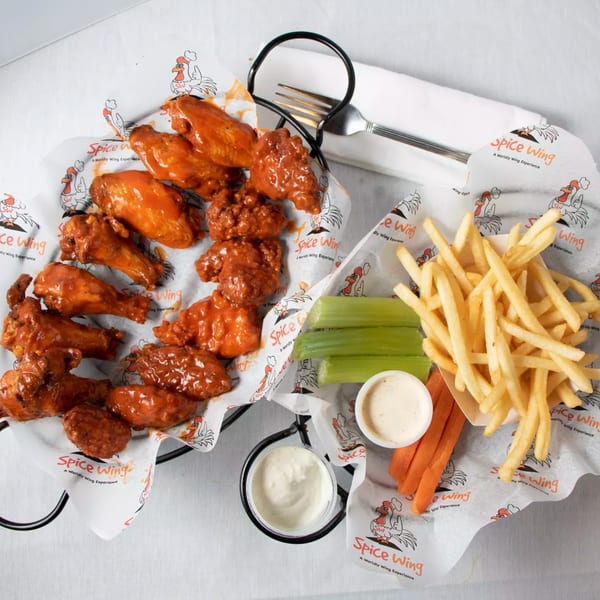 Spice Wing's buffalo wings, fries, celery, carrots, and dipping sauces in two wire baskets.