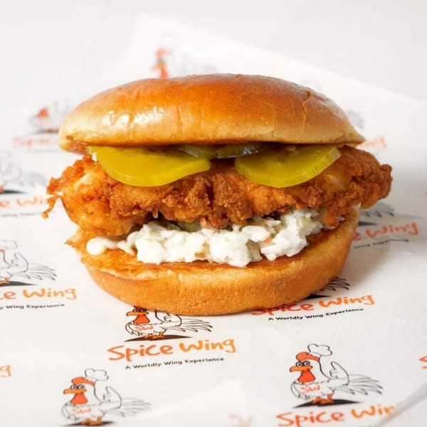 Spice Wing's fried chicken sandwich with pickles and coleslaw on a brioche bun.
